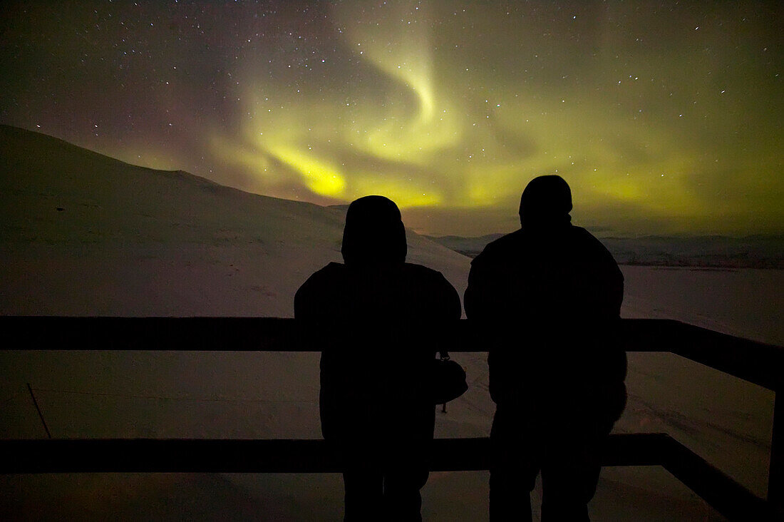 Two tourists watching Aurora Borealis from Aurora Sky Station, Abisko, Sweden