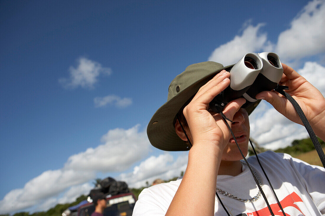 Young man looking through binoculars, Tanzania