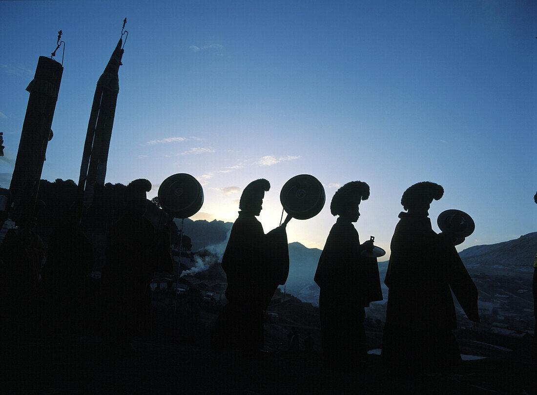 Monks carry drums, cymbols and banners before dawn to go and perform giant thangka ceremony as part of the Monlam (Tibetan New Year) festival, Sertang Monastery, Langmusi, Amdo, Eastern Tibet.