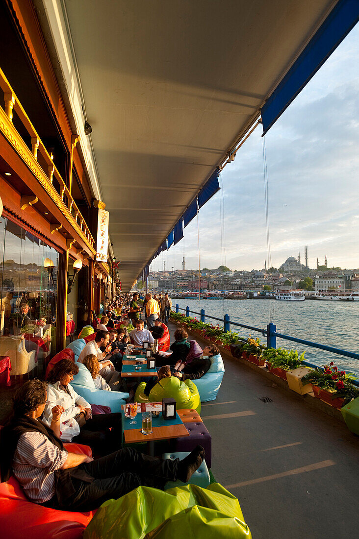 Bars and along the bottom of Galata Bridge at night with the New Mosque behind, Istanbul Turkey