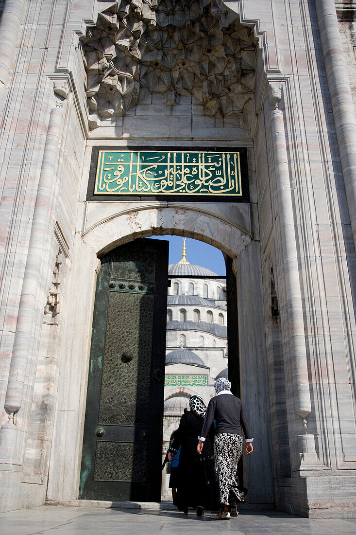 Women in headscarves entering doorway at Blue Mosque, Istanbul, Turkey