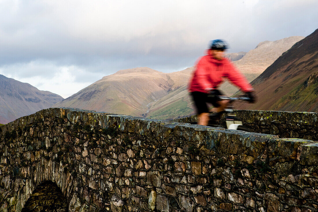 Mountain biker on stone bridge in Wasdale, Lake District, England.
