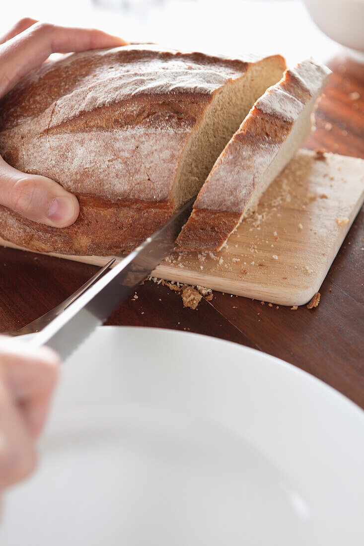 Close-up of a person's hand cutting bread