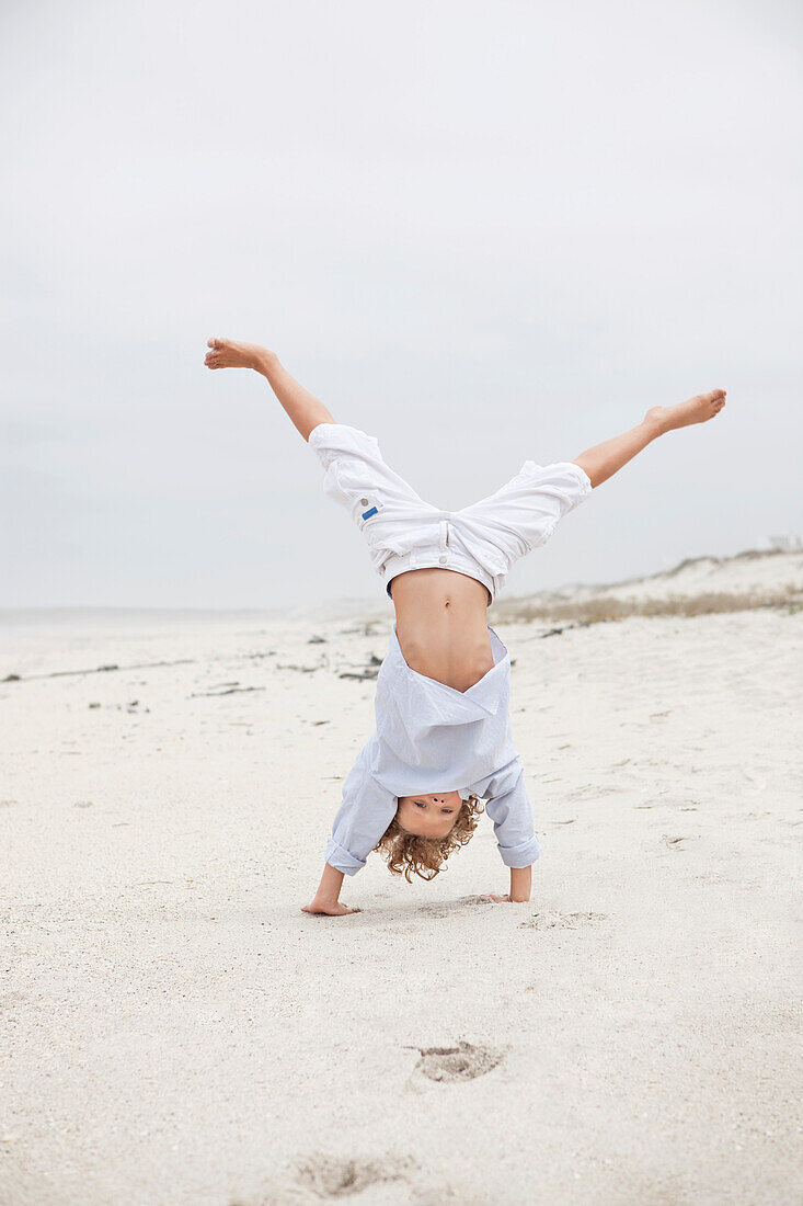 Boy doing handstand on beach