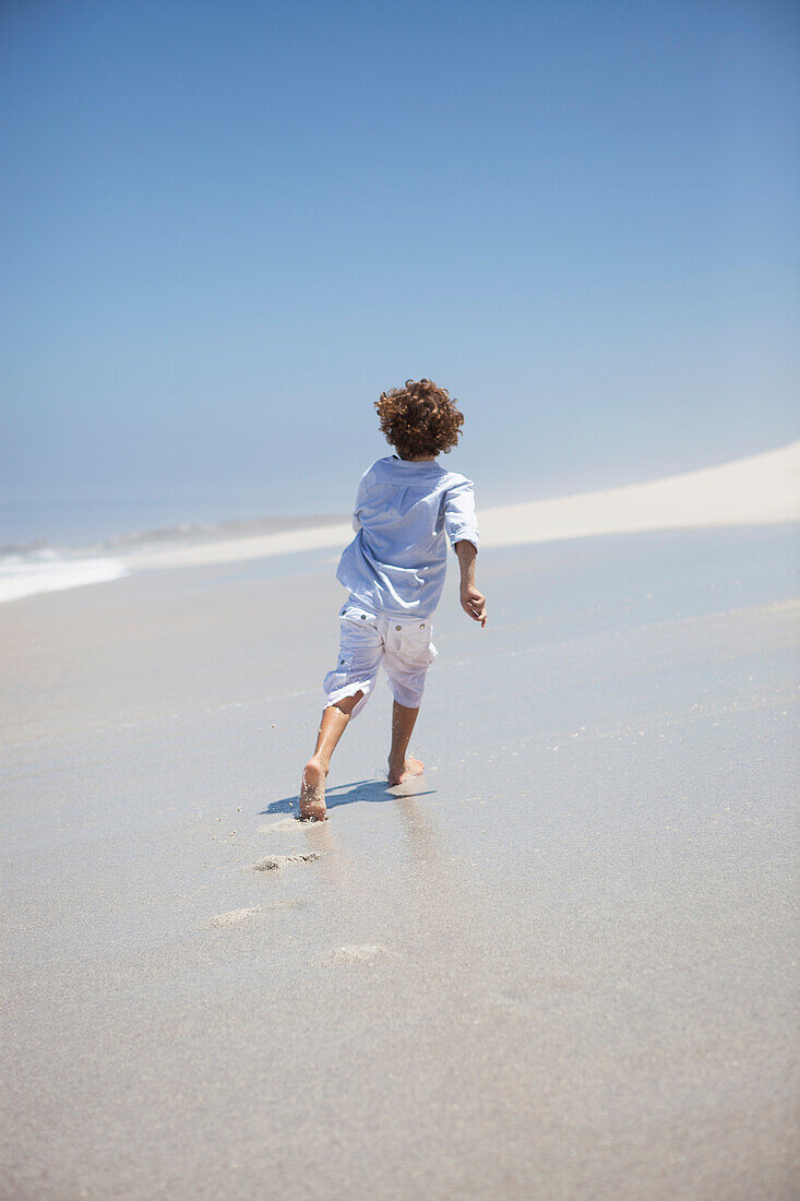 Rear view of a boy running on beach