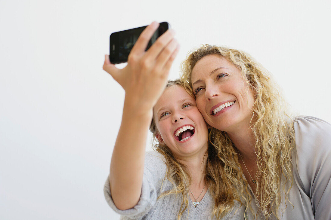 Girl with her mother taking picture of themselves with a mobile phone