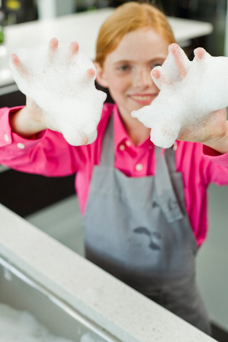 Portrait of a girl showing her hands covered in soap suds