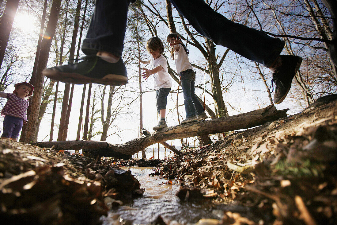 Children playing along the lakeshore, jumping over a stream, Leoni castle grounds, Leoni, Berg, Lake Starnberg, Bavaria, Germany