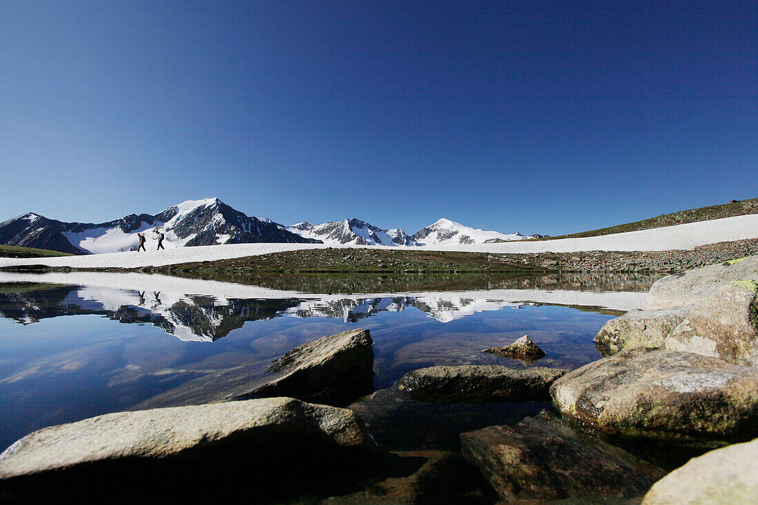 Bergsteiger am Brizzisee, Spiegelung der Berge im See, Mutmal und Similaun im Hintergrund, Ötztaler Alpen, Tirol, Österreich