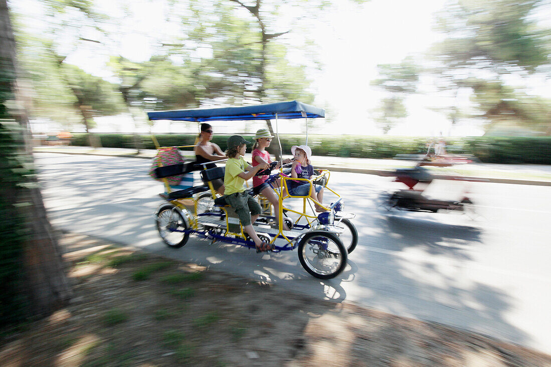 Family in a four person carriage cycle, Lido di Venezia, Venice, Veneto, Italy