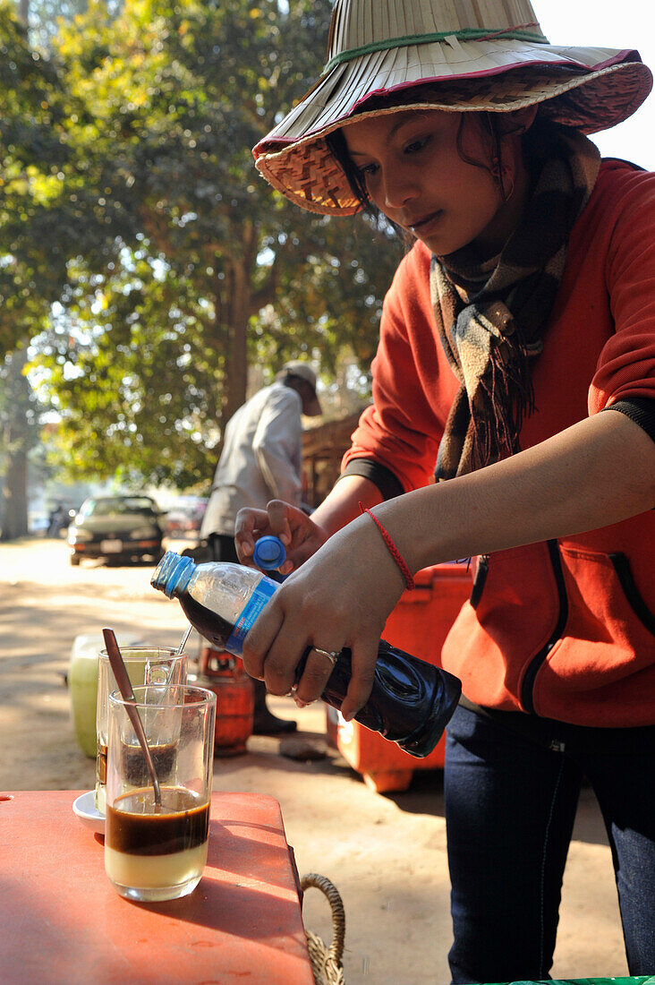 Junge kambodschanische Frau schenkt Milchkaffee ein, am Bayon Tempel, Angkor Thom, Angkor, Kambodscha, Asien