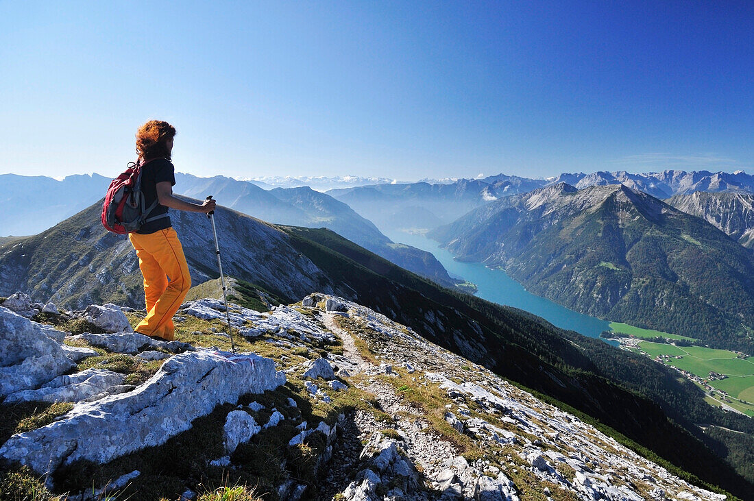 Woman walking at Unnutz with view to lake Achensee, Rofan range and Alpine main ridge, Unnutz, Unnuetz, Rofan, Tyrol, Austria