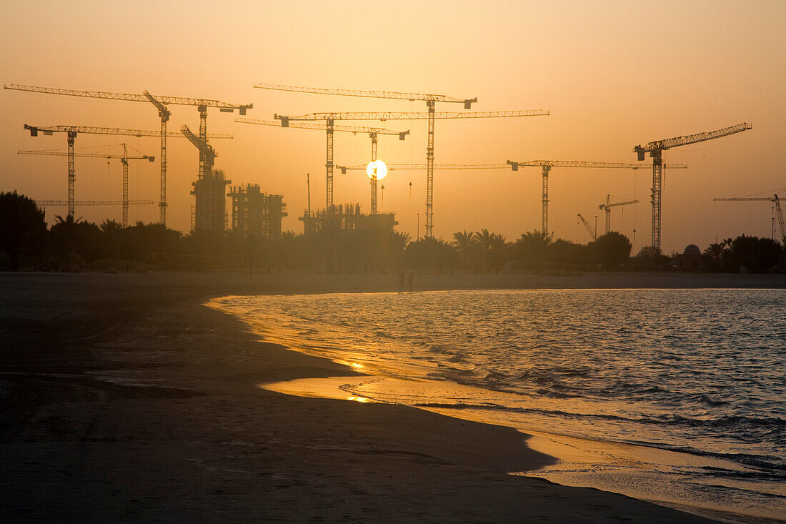 Strand und Baukräne bei Sonnenuntergang, Abu Dhabi, Abu Dhabi, Vereinigte Arabische Emirate