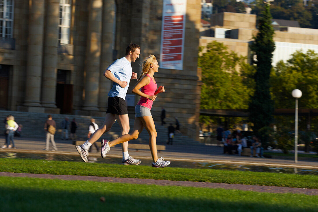 Young couple jogging, Upper Castle Garden, Staatstheater, Stuttgart, Baden Wurttemberg, Germany