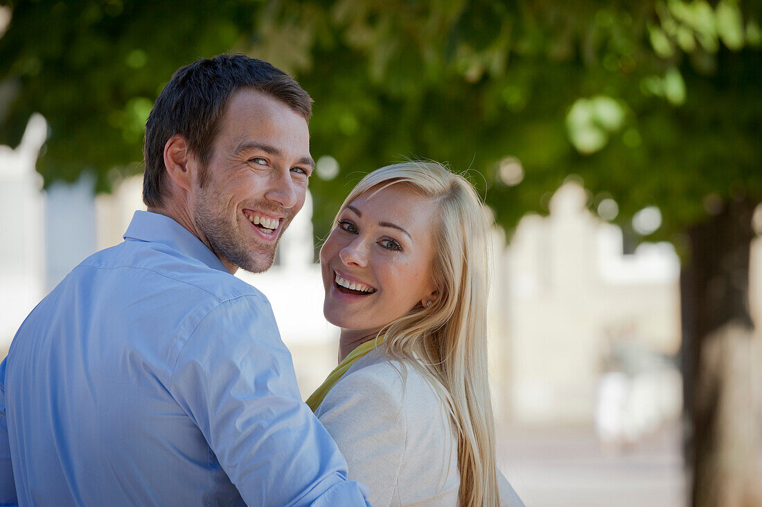 Young couple smiling to the camera, Schlossplatz, New Castle, Stuttgart, Baden Wurttemberg, Germany