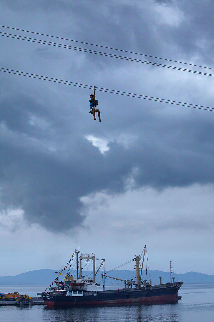 Man on zipline over bay of Legazpi City, Legazpi City, Luzon Island, Philippines, Asia