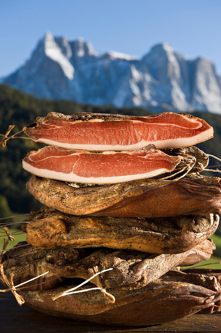 A pile of smoked bacon in front of Schlern mountain range, Kastelruth, Alto Adige, South Tyrol, Italy, Europe
