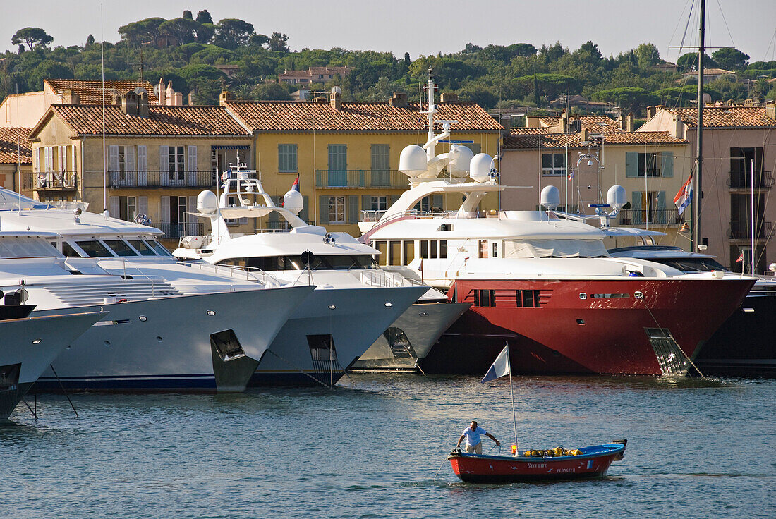 France, Var, Riviera, Saint-Tropez Harbour. Fisherman boat in front, luxurious yachts at rear