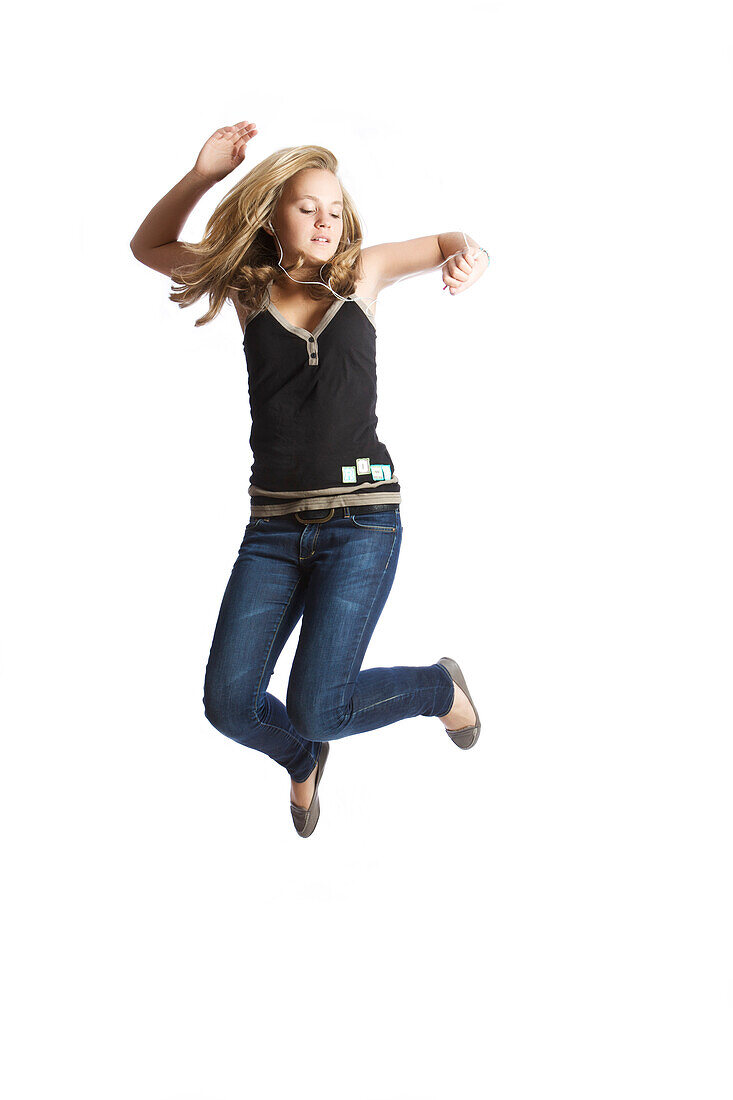 Teenage girl jumping, listening to MP3 player