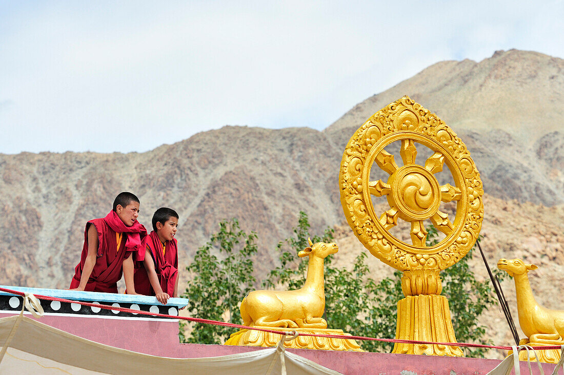 Novices looking from rooftop with wheel of life, monastery festival, Phyang, Leh, valley of Indus, Ladakh, Jammu and Kashmir, India