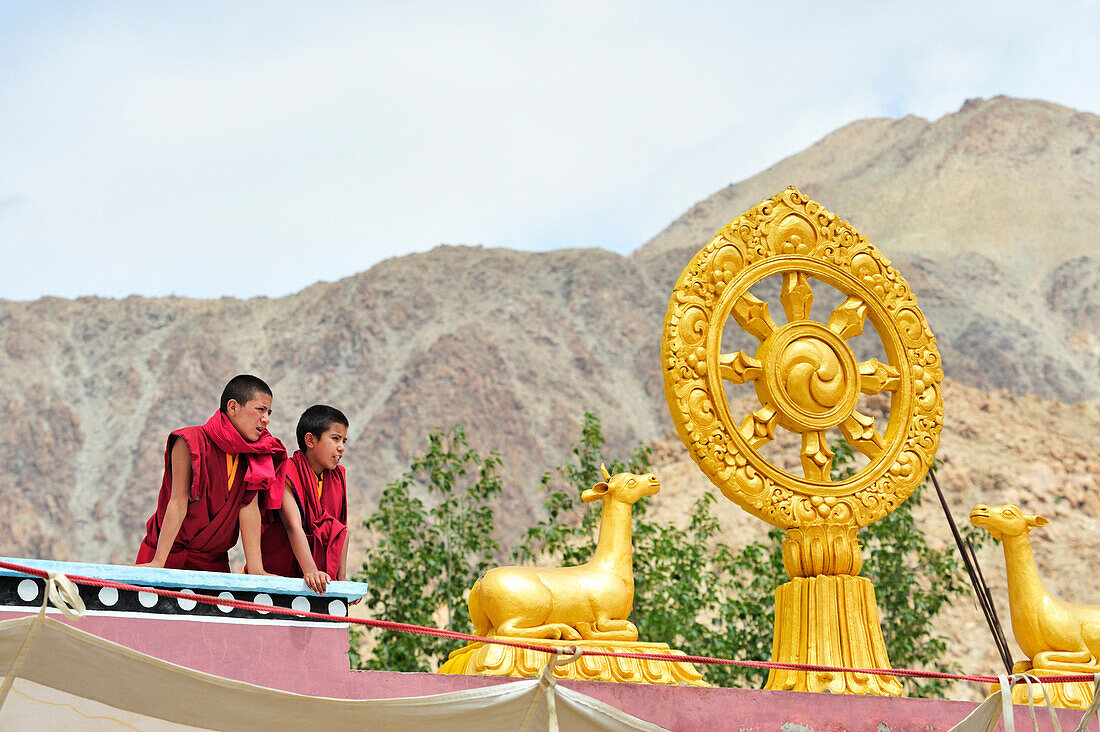 Novizen schauen vom Dach mit Rad der Lehre herab auf Klosterfest, Phyang, Leh, Industal, Ladakh, Jammu und Kashmir, Indien