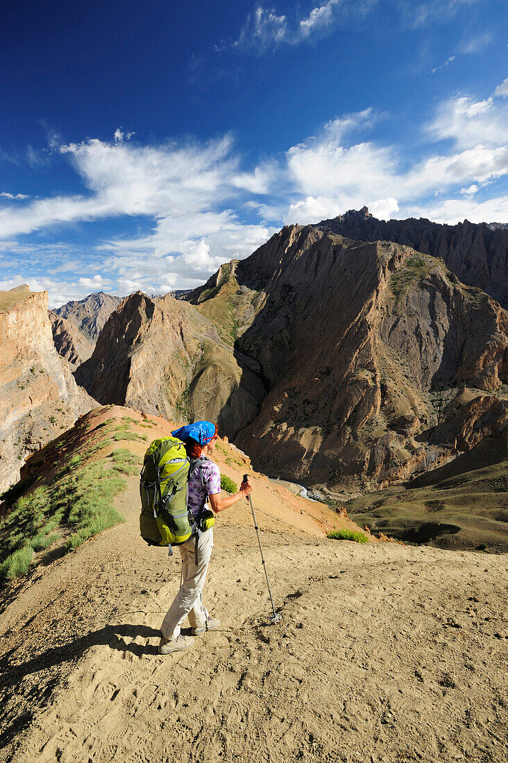 Frau mit Rucksack wandert über eine Schlucht, Snertse, Großer Zanskar Trek, Zanskargebirge, Zanskar, Ladakh, Jammu und Kashmir, Indien