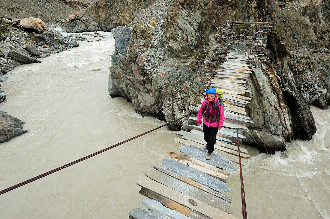 Frau überquert Fluß auf einer Hängebrücke, zwischen Phuktal und Testa, Großer Zanskar Trek, Zanskargebirge, Zanskar, Ladakh, Jammu und Kashmir, Indien