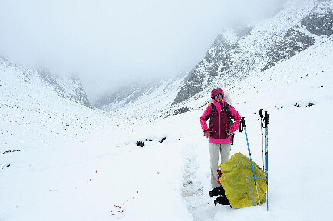Frau steht auf einem verschneitem Weg, Shingo La, Großer Zanskar Trek, Zanskargebirge, Zanskar, Ladakh, Jammu und Kashmir, Indien