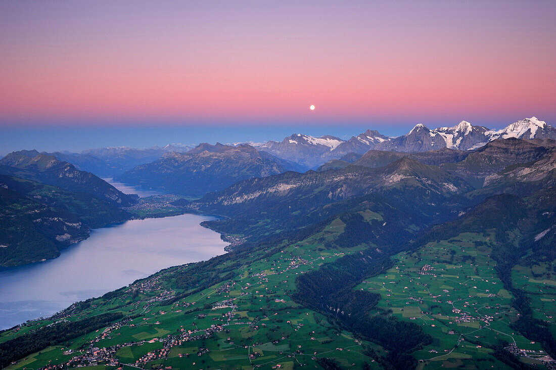 View from mount Niesen over Lake Thun to Wetterhorn, Eiger, Moench and Junfrau with full moon, UNESCO World Heritage Site Jungfrau-Aletsch protected area, Bernese Oberland, canton of Bern, Switzerland