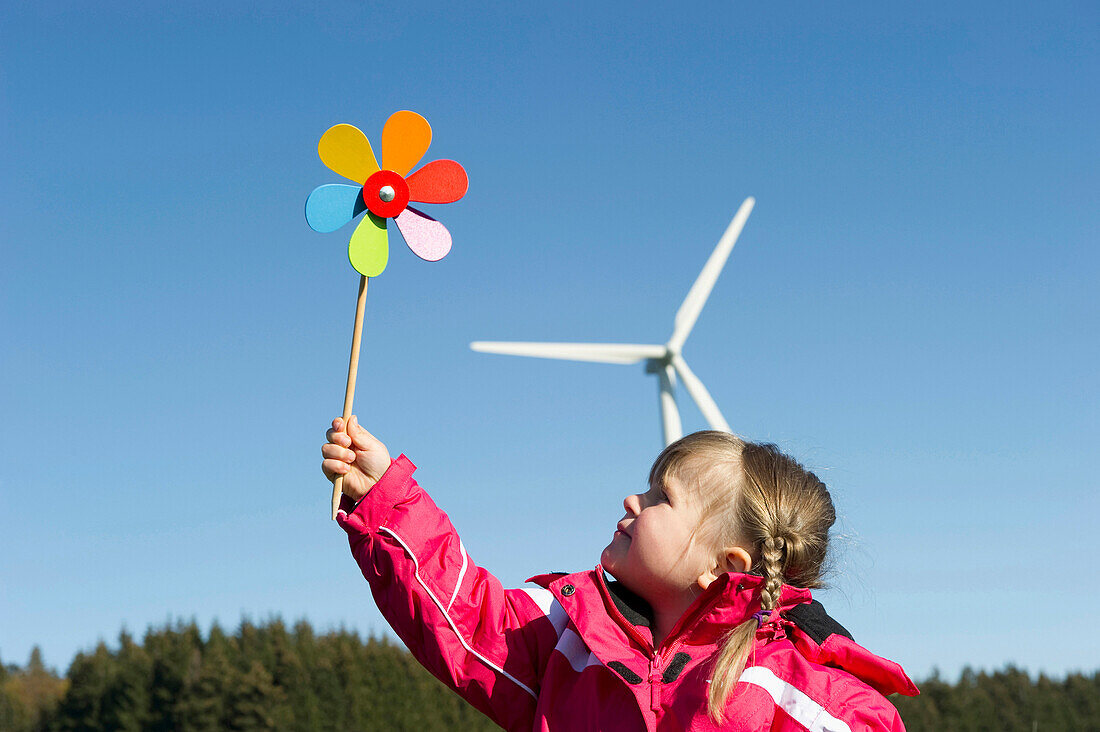 Little girl with a windmill toy, wind turbine in the background, Black Forest, Baden-Wurttemberg, Germany