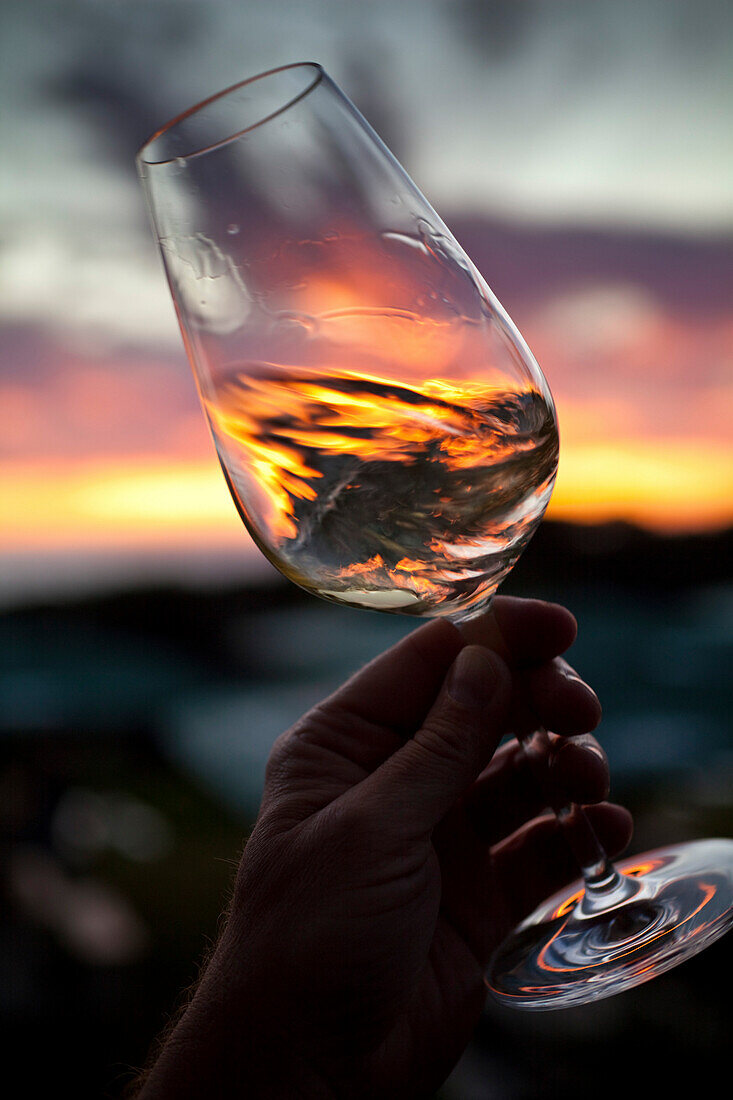 Hand mit Weinglas im Gegenlicht bei Sonnenuntergang, Stellenbosch, Westkap, Südafrika, Afrika
