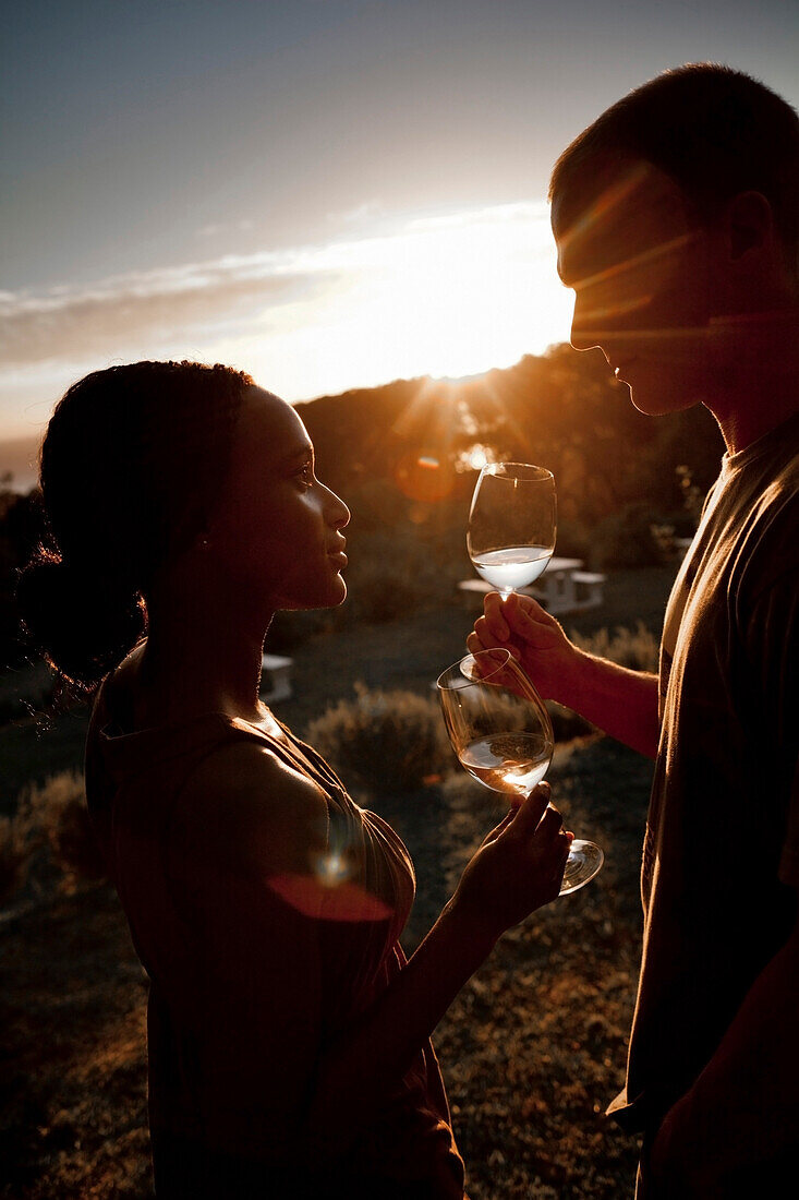 Man und woman enjoying a glass of white wine at sun-set, Stellenbosch, Western Cape, South Africa