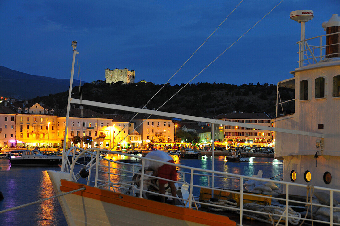 Boat entering the harbour of Senji at night, Senj castle in the background, near Velebit, Adria, Croatia
