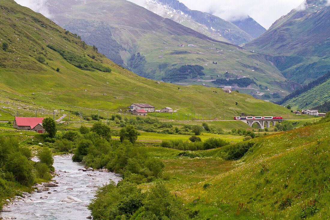 Urserental mit Fluss Furkareuss, im Hintergrund der Glacier Express, Andermatt, Uri, Schweiz
