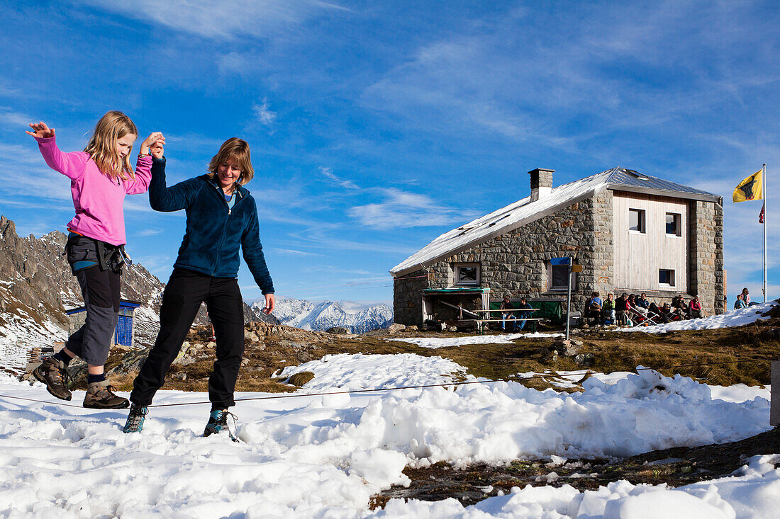 A woman helping a girl balance on a slackline at the Sewenhut, SAC Swiss Alpine-Club, Swiss Alps, Kanton Uri, Switzerland