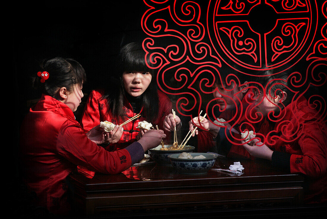 Chinese girls eating with chopsticks in Pingyao, a UNESCO World Heritage Site, Shanxi, China