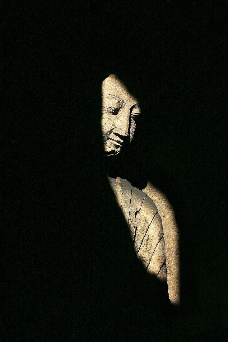 Buddha statue in shadows, Yungang Caves, Wuzhou Shan mountains, China