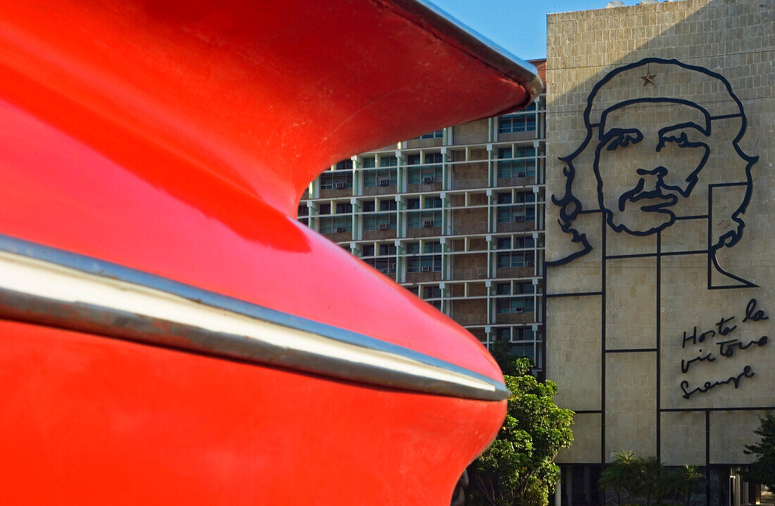 A detail of a classic 50's American car in front of  the imposing image of Che Guevara on the facade of the Ministry of the Interior building in the Plaza de la Revolucion, Havana, Cuba.