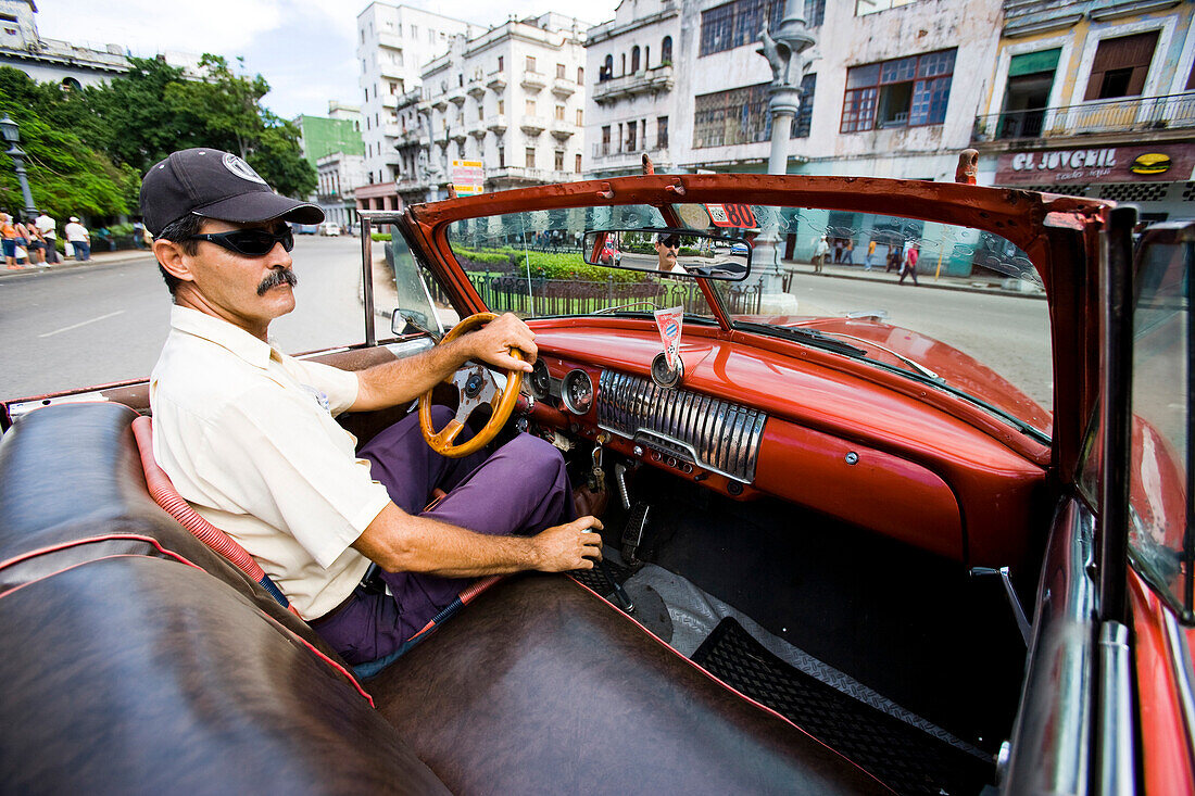 Man driving a Chevvy through Old Town, Havana, Cuba
