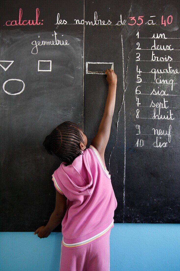 Sénégal, Dakar, Primary schoolgirl writing on the blackboard