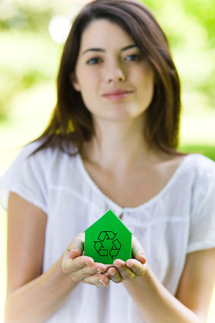 Young woman holding green model house with recycling sign