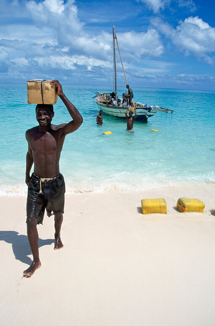 Man carrying box on head on beach, Vamizi Querimbas, Mozambique