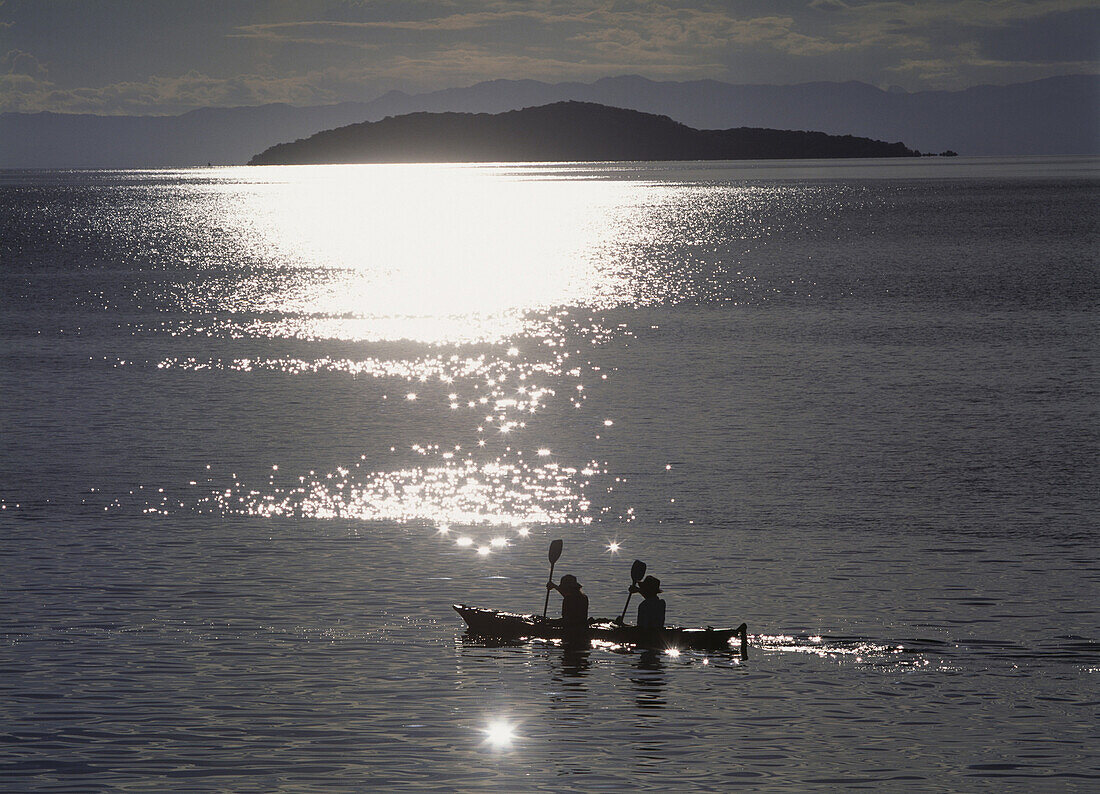 Fishermen going past the island of Domwe at dusk, Lake Malawi, Malawi