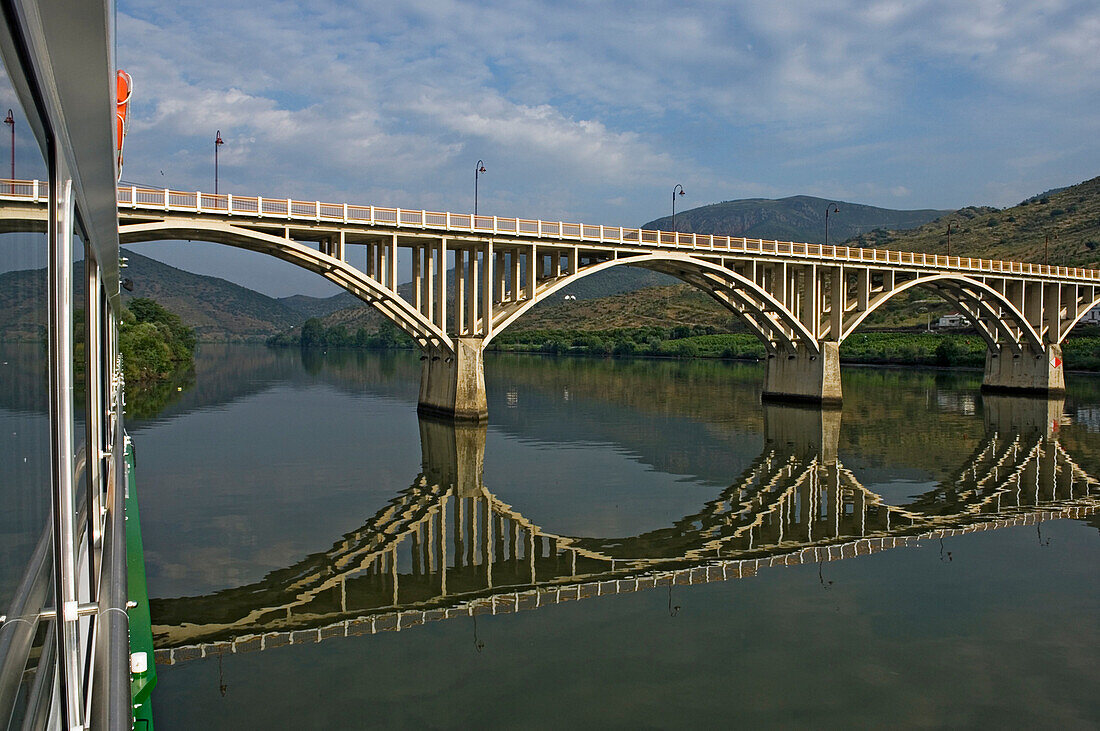 Cruise boat passing the bridge at Barca d'Alva, Douro Valley. Portugal