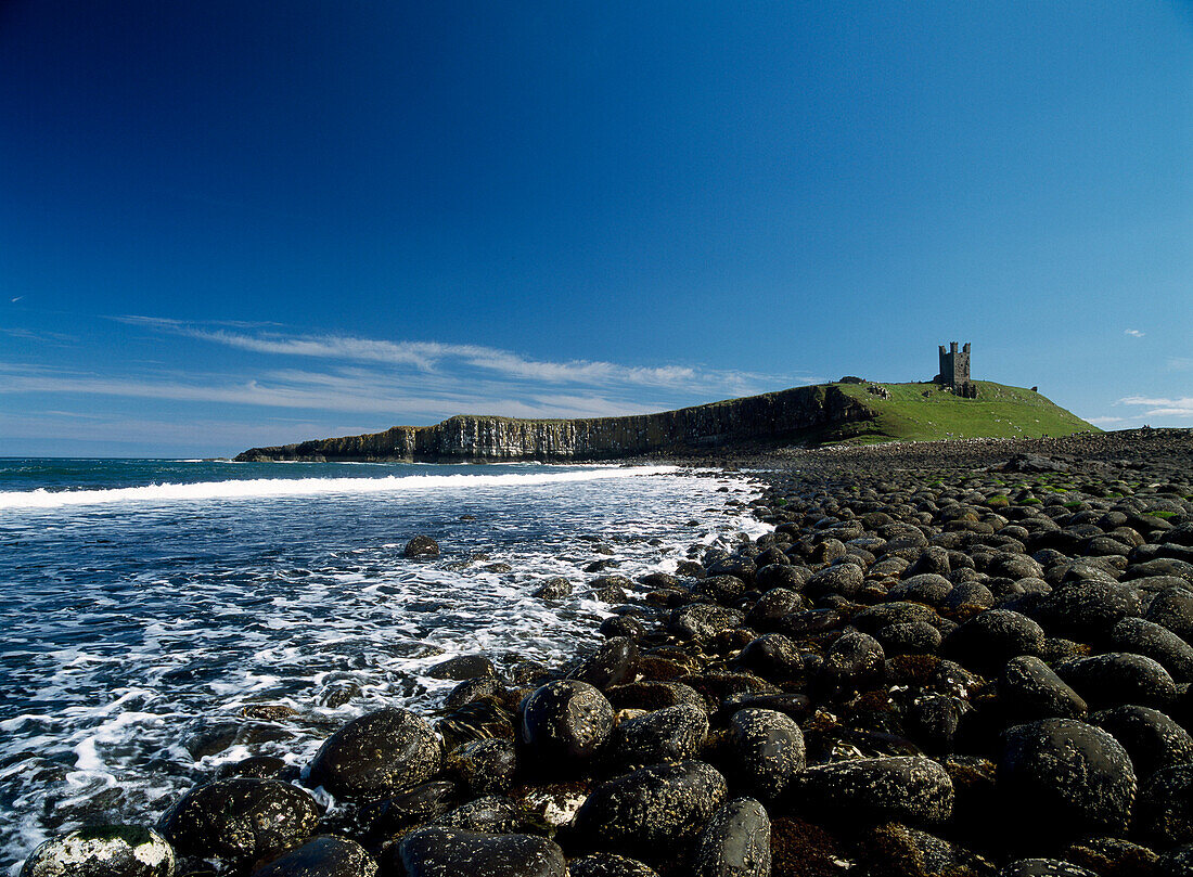 Looking over boulders to Dunstanburgh Castle, Northumberland, England