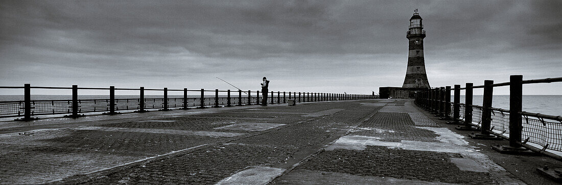 Fisherman on end of Roker pier beside lighthouse, Sunderland, Tyne & Wear, UK
