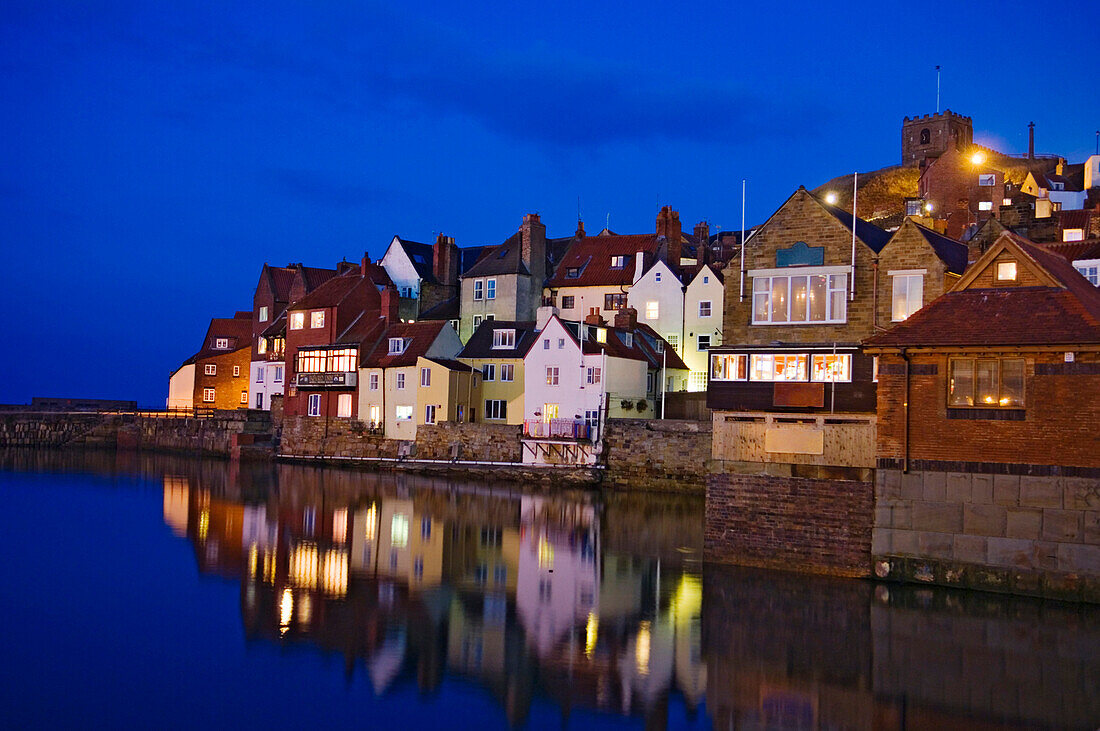 Houses and their reflection in the river in the historic town of Whitby, Yorkshire, England, United Kingdom.