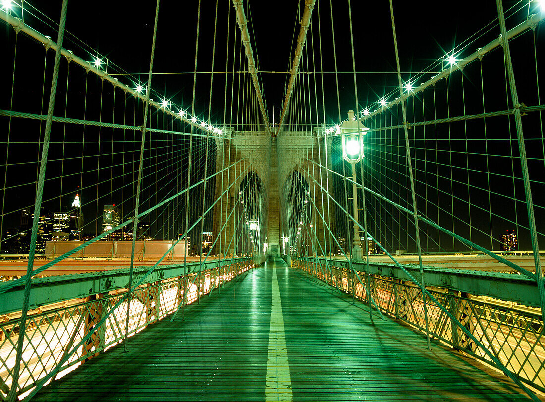 Looking along walkway on the Brooklyn Bridge at night, New York, USA