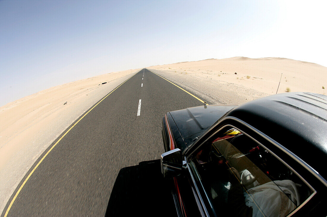 Car driving along remote desert road, Yemen