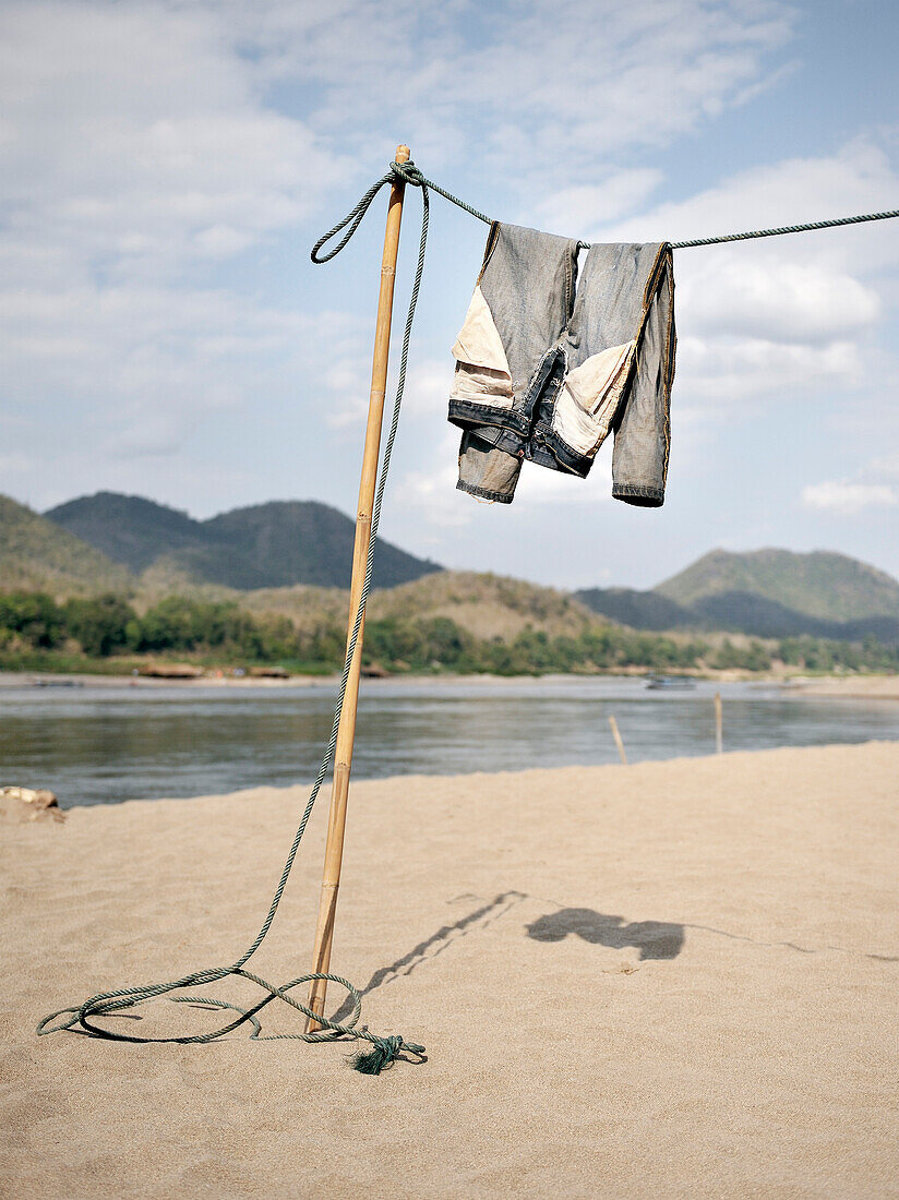 Hose hängt zum Trocknen an Wäscheleine am Ufer des Mekong Fluss, Sandstrand, Luang Prabang, Laos